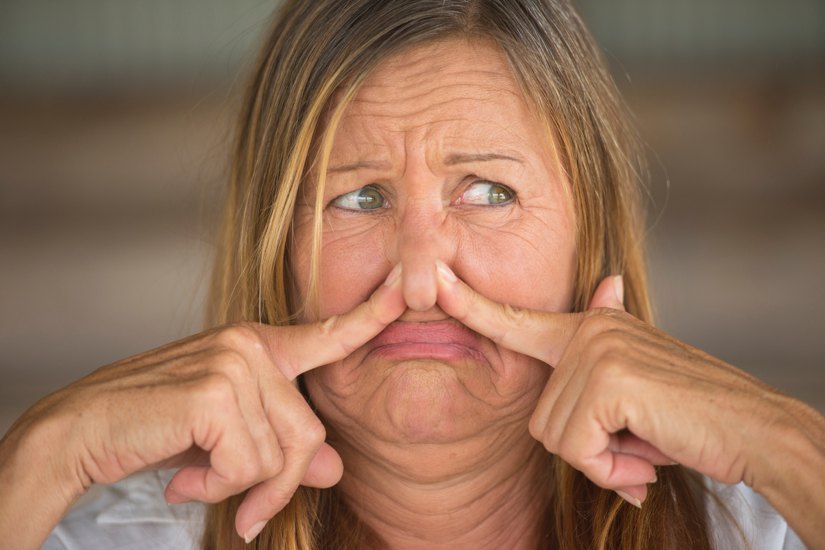 Woman annoyed by smelly air blocking nose